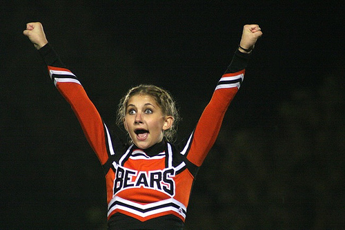Young cheerleader screaming with hands in the air